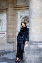 Woman in a black suit standing against a stone wall with architectural details. Office outfit. Work outfit. business outfit. Women suit.  