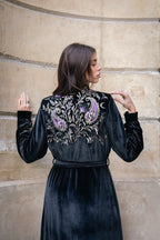 Woman wearing a black velvet abaya with intricate embroidery..