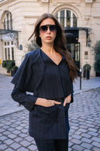 Woman in a dark pinstripe suit standing on a street with classical architecture in the background