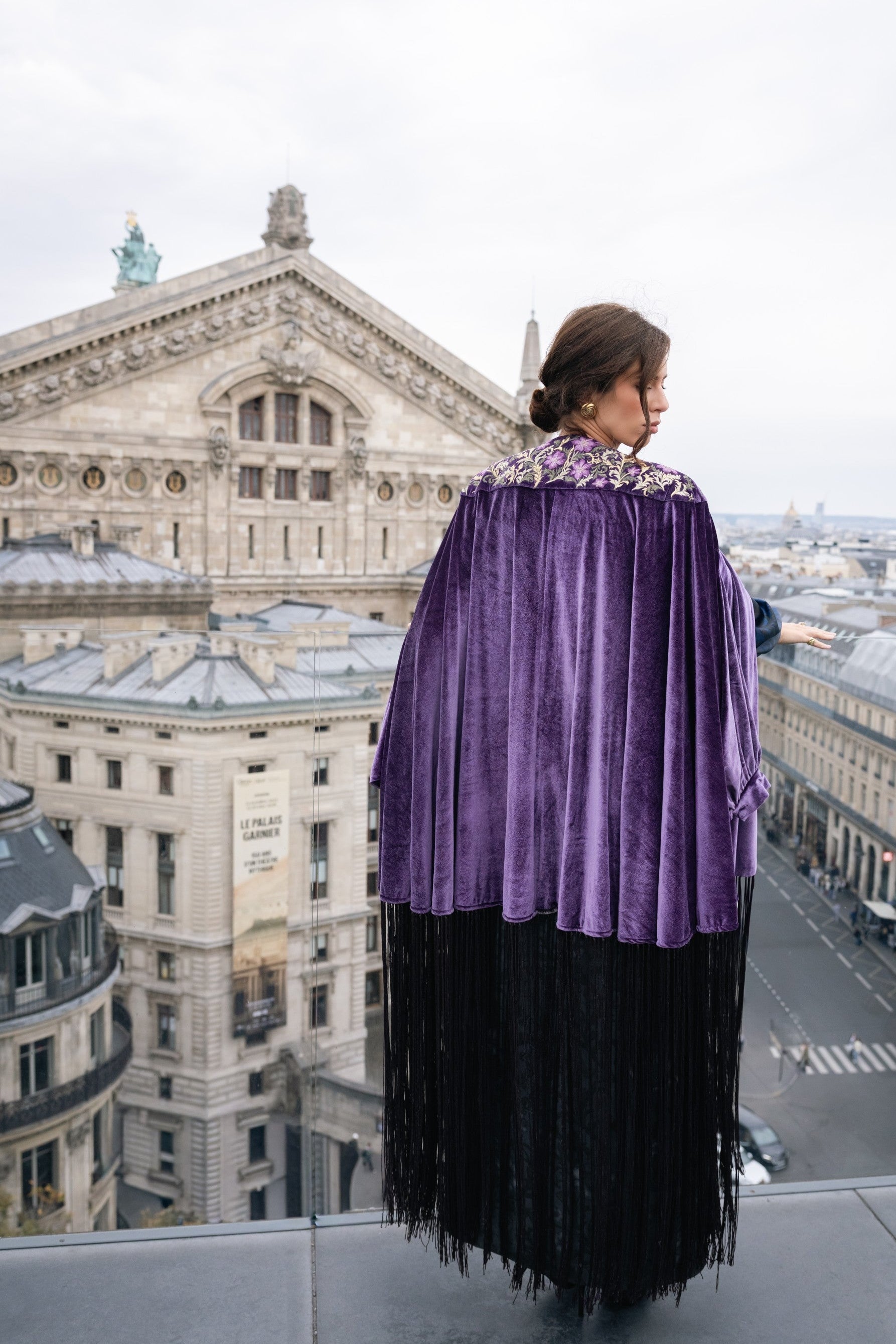 Person wearing a purple cape with a cityscape in the background. Opera coat. Eid look. Eid outfit. Ramadan outfit