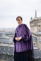 Woman wearing a purple velvet coat with a cityscape background. velvet cape. NYE party. Christmas party outfit. Parisian style. Party look. Eid outfit. Eid look. 