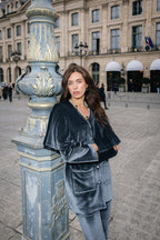 Woman in a silver gray velvet suit outfit standing.